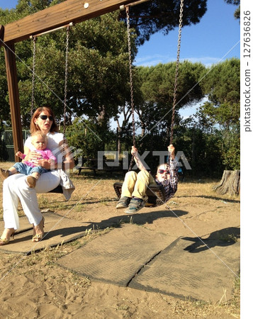 Grandmother and Children Enjoying Swings in Park Grandmother and Children Enjoying Swings in Park 127636826