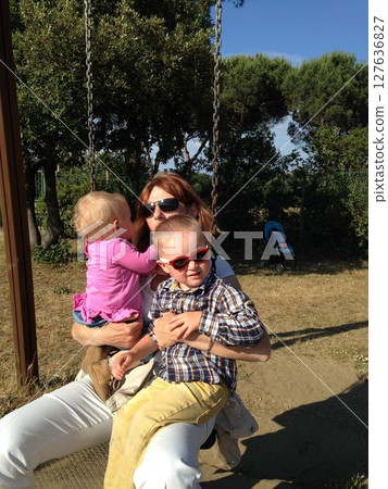Grandmother and Grandchildren Sharing a Joyful Swing Ride 127636827