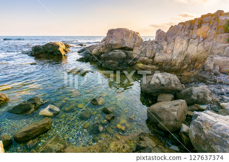 beautiful sunrise at the black sea. outdoor adventure. rocky coast and clouds on the blue sky in morning light. summer vacations and weather change concept. natural environment 127637374
