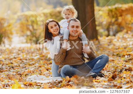 Family with cute little daughter. Father in a brown sweater. Family in a autumn field Family with cute little daughter. Father in a brown sweater. Family in a autumn field 127637387