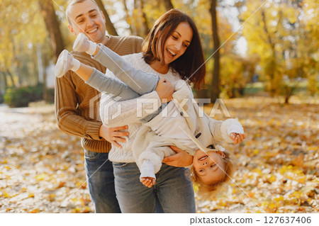 Family with cute little daughter. Father in a brown sweater. Family in a autumn field Family with cute little daughter. Father in a brown sweater. Family in a autumn field 127637406