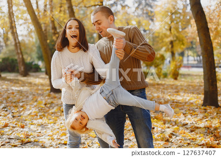Family with cute little daughter. Father in a brown sweater. Family in a autumn field Family with cute little daughter. Father in a brown sweater. Family in a autumn field 127637407
