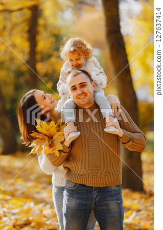 Family with cute little daughter. Father in a brown sweater. Family in a autumn field 127637414