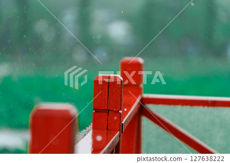 朦朧雨景下的紅色木製欄桿 127638222