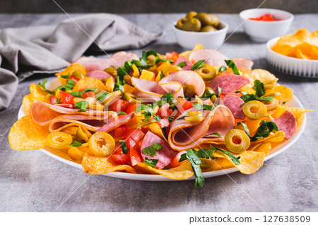 Charcuterie nachos with chips, salami, cheese and olives on a plate on a table Charcuterie nachos with chips, salami, cheese and olives on a plate on a table 127638509