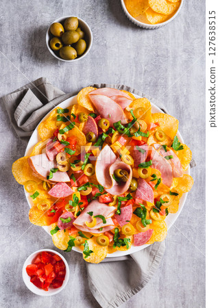 Snack trend Charcuterie nachos with potato chips on plate on table top and vertical view 127638515