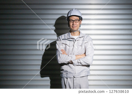 A man in work clothes with his arms folded A man in work clothes with his arms folded 127638610
