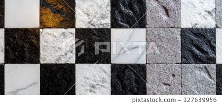 Textured checkerboard surface made of various marbles including Calacatta, Statuario, Rosso Levanto, and black granite 127639956