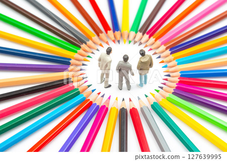 Three small figurines stand in the center of a vibrant circle of colorful pencils, Three small figurines stand in the center of a vibrant circle of colorful pencils, 127639995