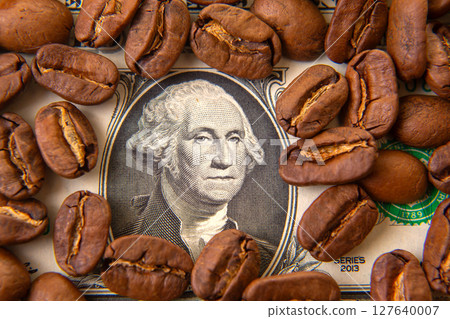 Roasted coffee beans scattered on a US dollar bill with George Washington's portrait in the center 127640007