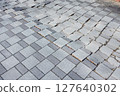 A photo of a brick road, some of which are broken. 127640302