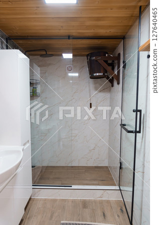 Modern Rustic Shower Room Interior Featuring Glass Enclosure, Wood Ceilings, Marble Tile Walls, Dark Wood Accents, and Minimalist Design. Modern Rustic Shower Room Interior Featuring Glass Enclosure, Wood Ceilings, Marble Tile Walls, Dark Wood Accents, and Minimalist Design. 127640465