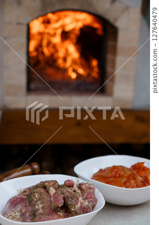 Rustic Stone Oven with Burning Fire, Raw Meat and Vegetable Bowls. Warm Tone Cooking Scene, Outdoor Kitchen, Culinary Preparation 127640479