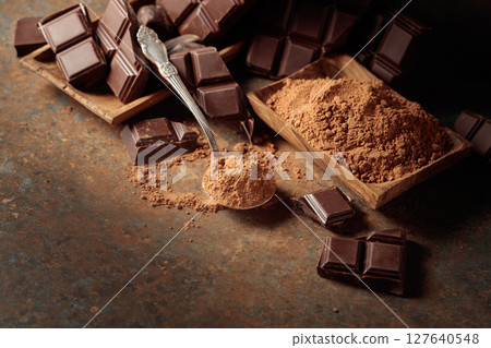 Broken bitter chocolate bar and cocoa powder. Broken bitter chocolate bar and cocoa powder. 127640548