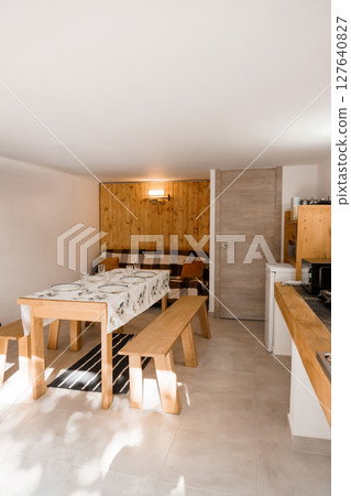 Cozy Alpine Dining Area Interior with Wooden Wall Accent, White Tablecloth, Bench Seating, and Modern Lighting in a Ski Lodge Style Space Cozy Alpine Dining Area Interior with Wooden Wall Accent, White Tablecloth, Bench Seating, and Modern Lighting in a Ski Lodge Style Space 127640827