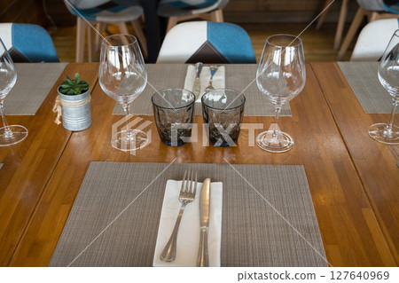 Elegant table setting with glassware and cutlery on wooden dining table 127640969