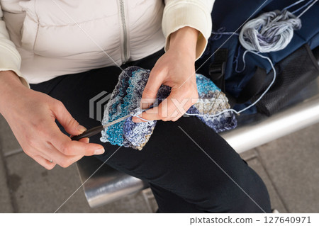 I Love Yarn Day. Female adult crocheting with multicolored yarn while seated on a bench I Love Yarn Day. Female adult crocheting with multicolored yarn while seated on a bench 127640971