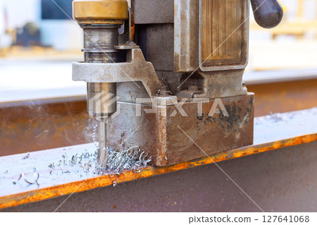 Drill tool efficiently drilling metal beams at construction site, with small shavings Drill tool efficiently drilling metal beams at construction site, with small shavings 127641068