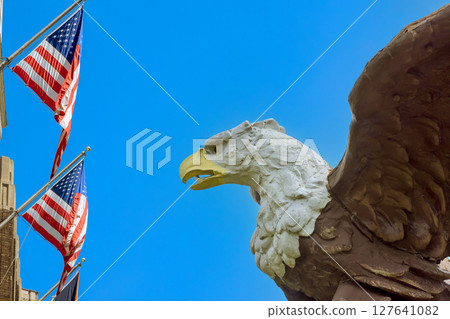 Eagle sculpture towers over American flags, creating patriotic atmosphere in an urban setting 127641082