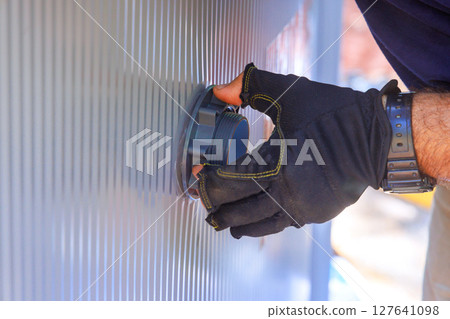 Worker in gloves adjusts valve on filtration system to swimming pool. 127641098