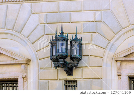 Vintage street lamp adorns wall of historical building, illustrating beautiful architectural design elegance. 127641109