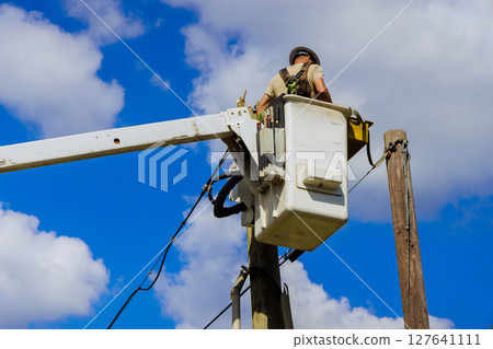 Worker is in lift, conducting repairs on power lines while ensuring safety efficiency after hurricane 127641111