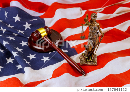 Judicial gavel Lady Justice statue are placed on an American flag, symbolizing law justice in United States. 127641112