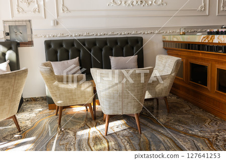 Morning sun lights up elegant cafe seating. Cozy atmosphere, stylish comfort, and relaxed social interaction in a chic modern interior. 127641253