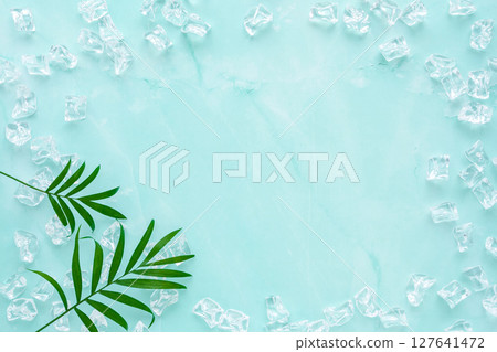 Ice and table palm leaves on a pale blue marbled background Ice and table palm leaves on a pale blue marbled background 127641472