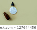 Flat lay bottle with a pipette and a cotton pad on a beige background. 127644456