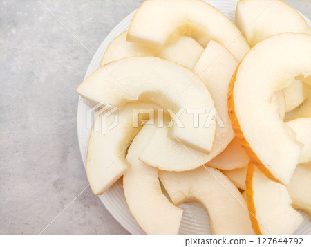 Slices of fresh canary melon presented on white plate Slices of fresh canary melon presented on white plate 127644792