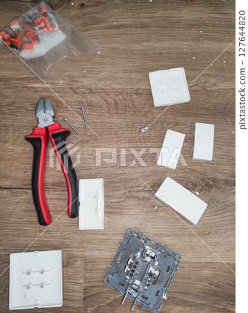 Electrician installing light switch on wooden surface 127644820
