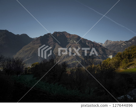 Scenic view of the aosta valley in italy, showcasing dramatic mountain ranges under a clear blue sky, with autumn foliage in the foreground Verres 127644896