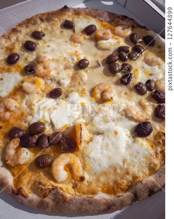 Freshly baked shrimp pizza with green olives, melted cheese, highlighting traditional italian flavors. Photographed in aosta during autumn 127644899