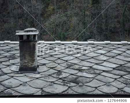 Weathered slate roof, rustic chimney nestled among dense autumn forest foliage in aosta, italy, highlighting seasonal tranquility pontboset Weathered slate roof, rustic chimney nestled among dense autumn forest foliage in aosta, italy, highlighting seasonal tranquility pontboset 127644906