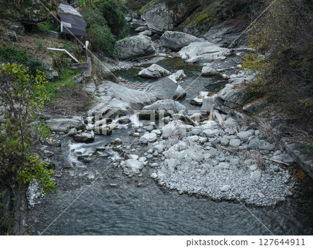 Winding stream flowing between rocky terrain in valle d'aosta, capturing autumn's golden palette amid rugged mountain scenery pontboset 127644911
