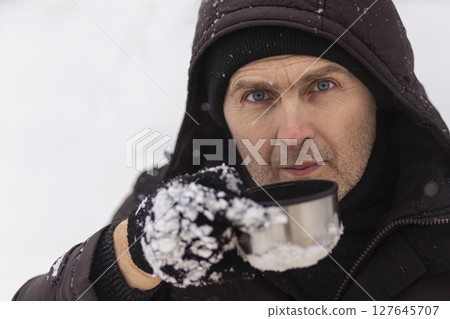 Close-up of a man drinking tea in winter. Close-up of a man drinking tea in winter. 127645707