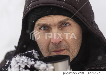 A man holds a mug against a background of snow. 127645713