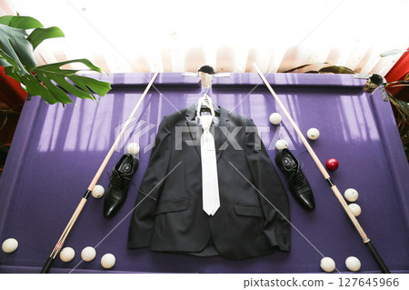 The groom's suit lies on the billiard table. 127645966