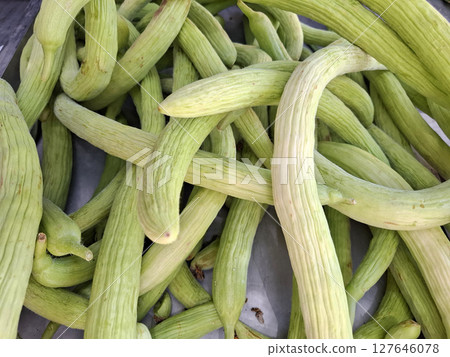 A vibrant display of alicante cucumbers is showcased at a bustling farmers market in Alficoz, Spain. Local vendors offer fresh produce, highlighting seasonal vegetables. 127646078