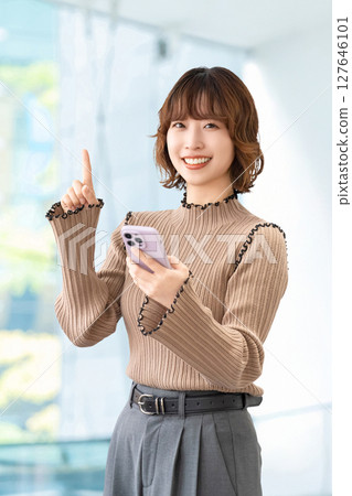 A smiling woman/businesswoman giving directions with a smartphone 127646101