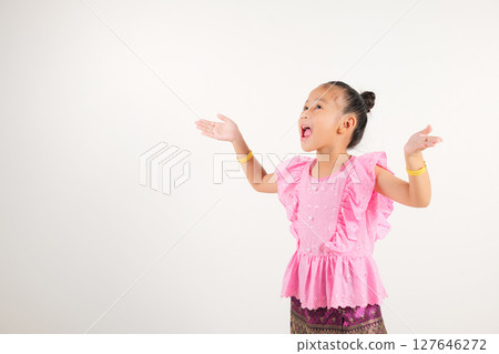 Portrait Thailand kid girl smiling traditional Thai dress costume raises fists in celebration of her success, studio isolated white background, kindergarten child saying yes with excitement winning 127646272
