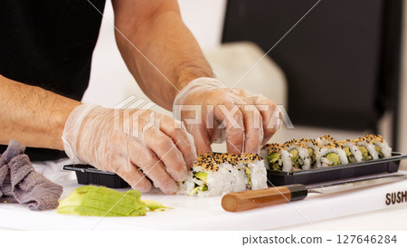 Chef Preparing Sushi Rolls in a Kitchen With Fresh Ingredients and Tools 127646284