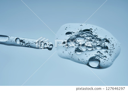 The texture of cosmetic serum in a pipette on a blue background. The texture of cosmetic serum in a pipette on a blue background. 127646297