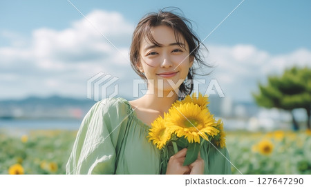 A woman wearing a light green dress is holding a sunflower 127647290