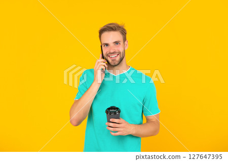 happy guy with coffee speak on phone on yellow background, conversation 127647395