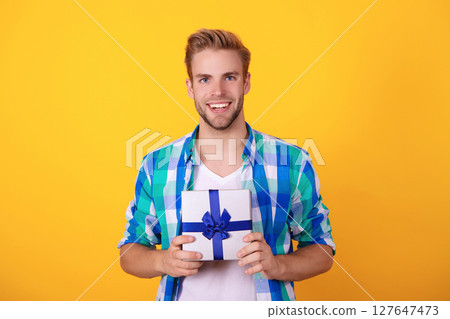 Mens day. Birthday party present. Man on February 14. Young guy hold present box for Valentines day. Happy anniversary. Man with gift isolated on yellow. Gift from the bottom of heart for mens day Mens day. Birthday party present. Man on February 14. Young guy hold present box for Valentines day. Happy anniversary. Man with gift isolated on yellow. Gift from the bottom of heart for mens day 127647473