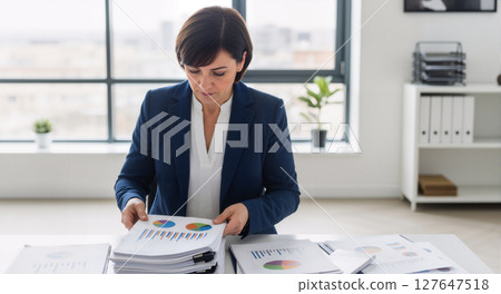 Businesswoman working with blueprints at her desk. 127647518