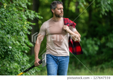 Strong sweating man work in forest. Lumberjack man in forest with axe. Lumberjack carries axe. Sweating man with axe. Lumberjack in woods with an ax. Lumberjack with heavy axe 127647559