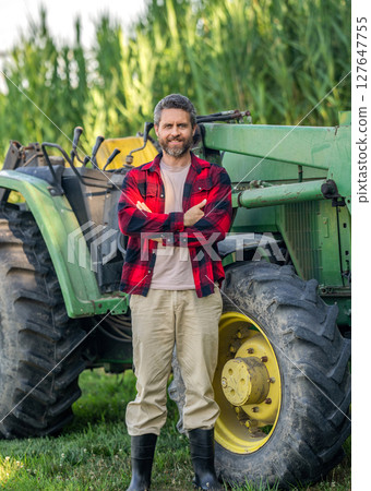 Tractor driver. Agriculture and field work. Farmer in field wearing gum boots with tractor outdoor. Crop harvesting. Agriculture machinery. Farmer with harvesting machinery. Mature man at tractor 127647755